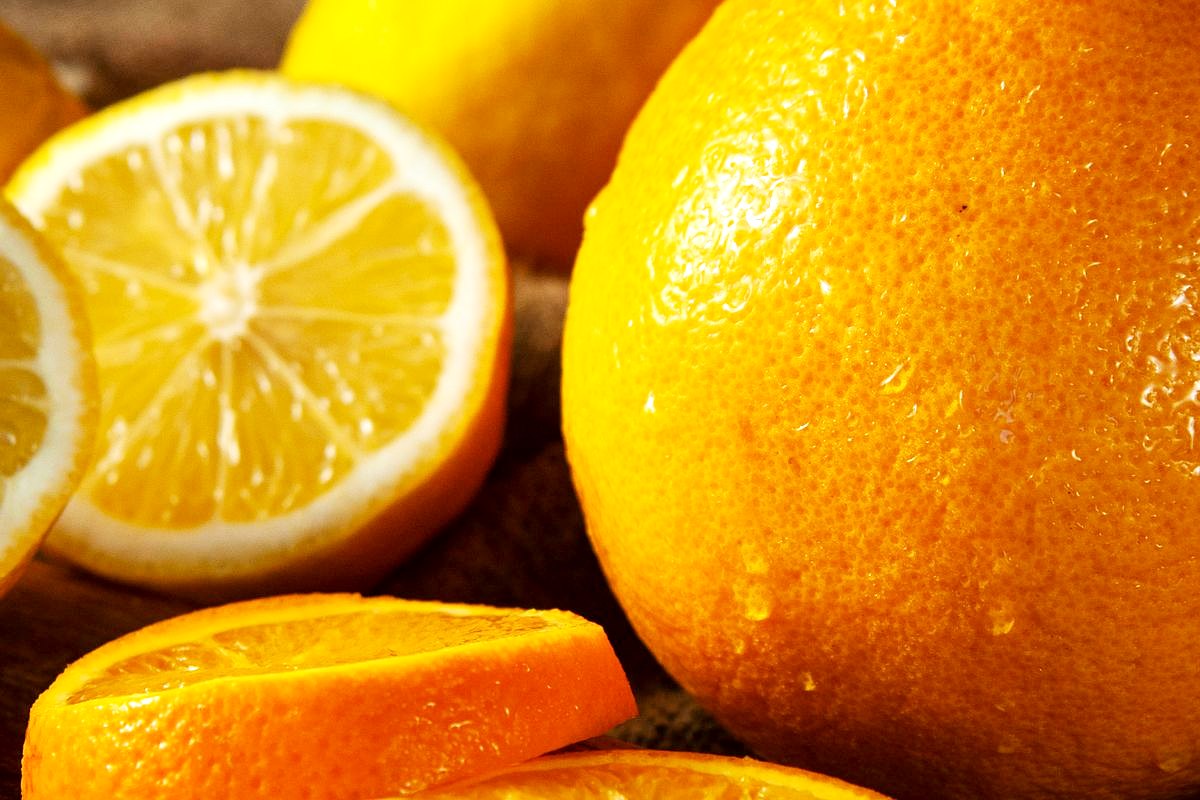 Frische Orangen und Zitronen, teils aufgeschnitten, auf einem Holzbrett